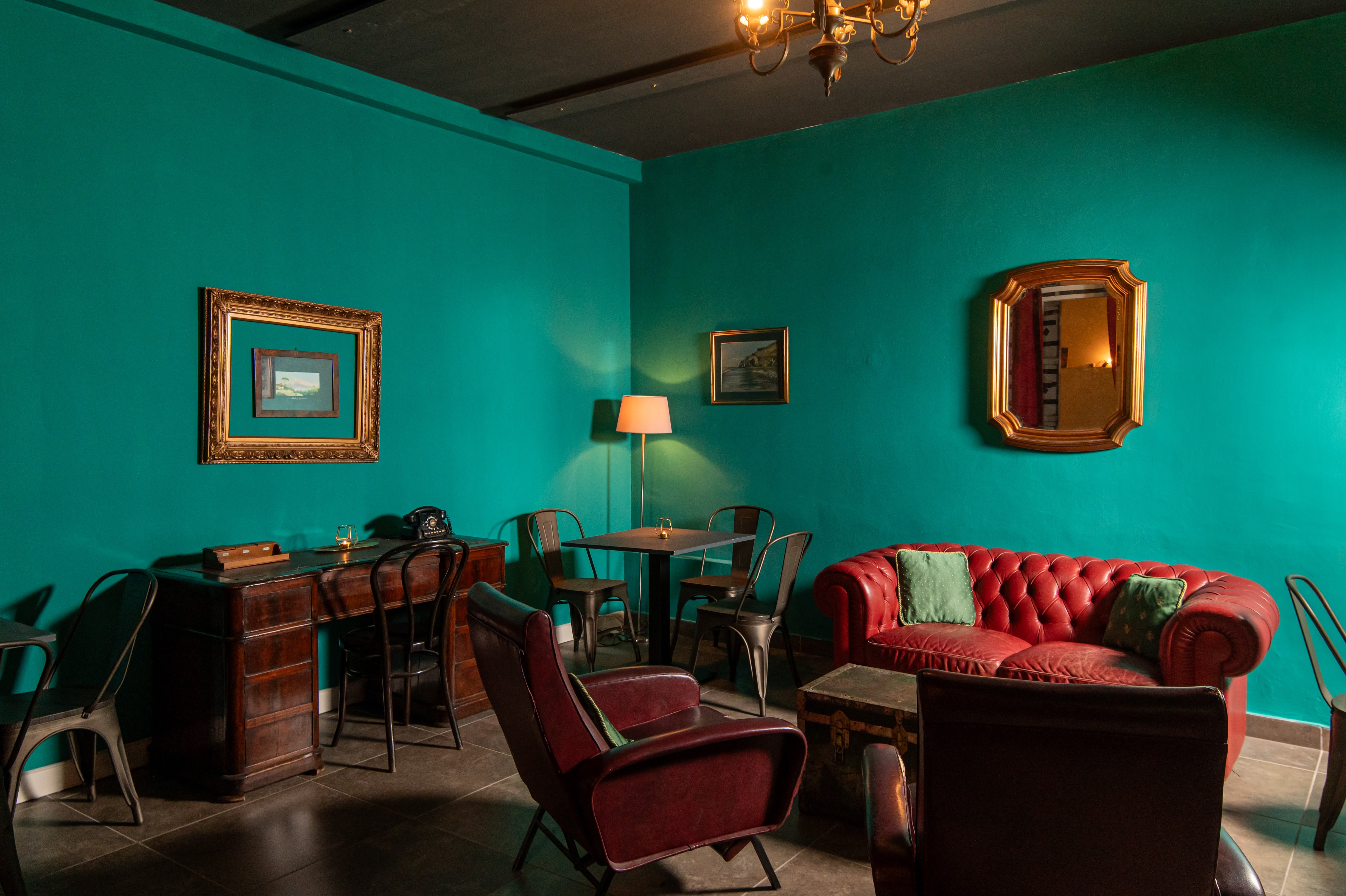 Interno di Yam Eventi a Napoli: salotto in stile speak-easy con pareti verdi, divano rosso e arredi retro del '900.